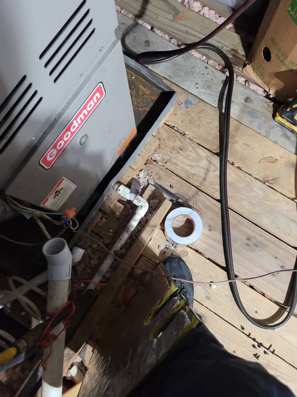 Furnace in an attic mid-repair with the attic decking opened up